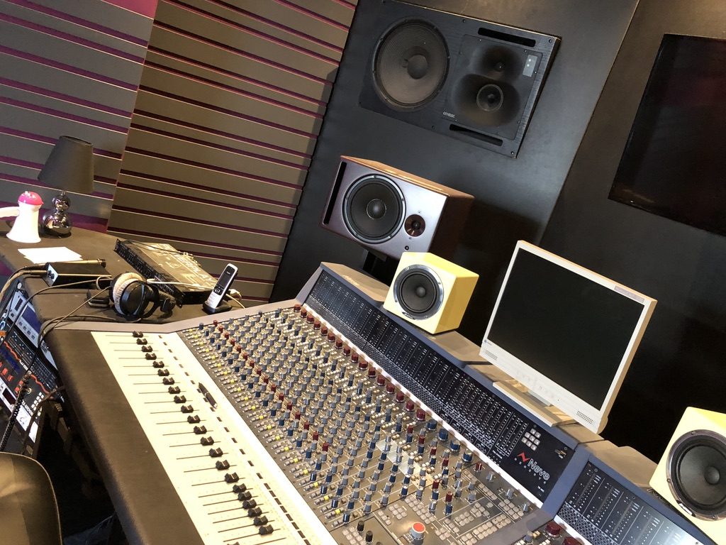Détail d’une console audio professionnelle dans une régie acoustique rose et noire