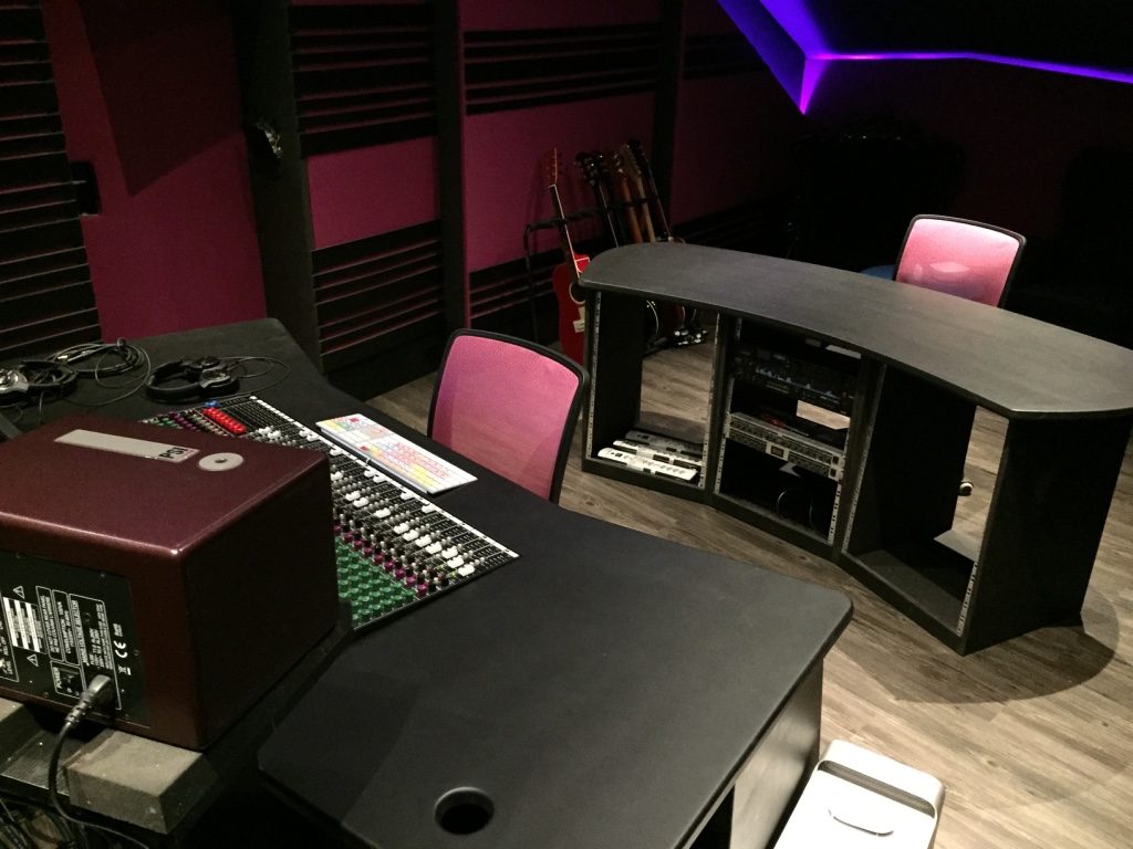 Mobilier studio noir avec racks intégrés et panneaux acoustiques roses
