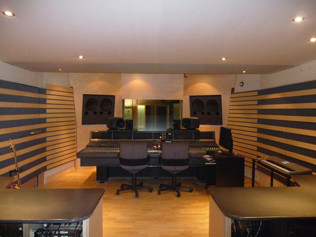 Régie studio classique avec console, fauteuils et panneaux acoustiques bois