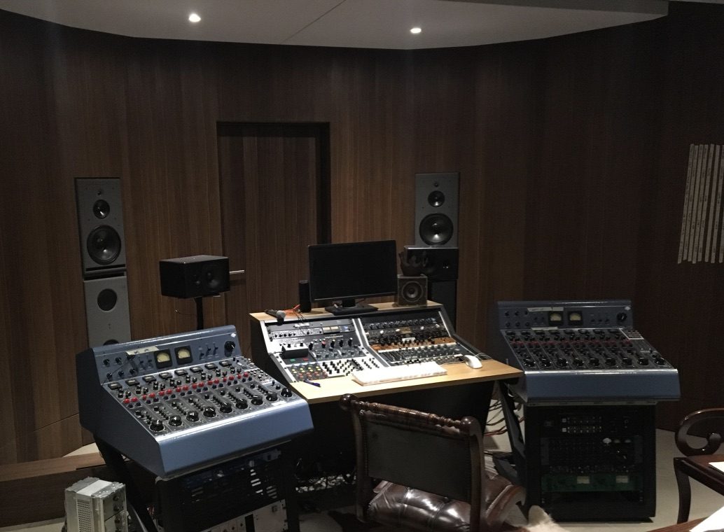 Régie audio sombre avec consoles analogiques et enceintes de monitoring