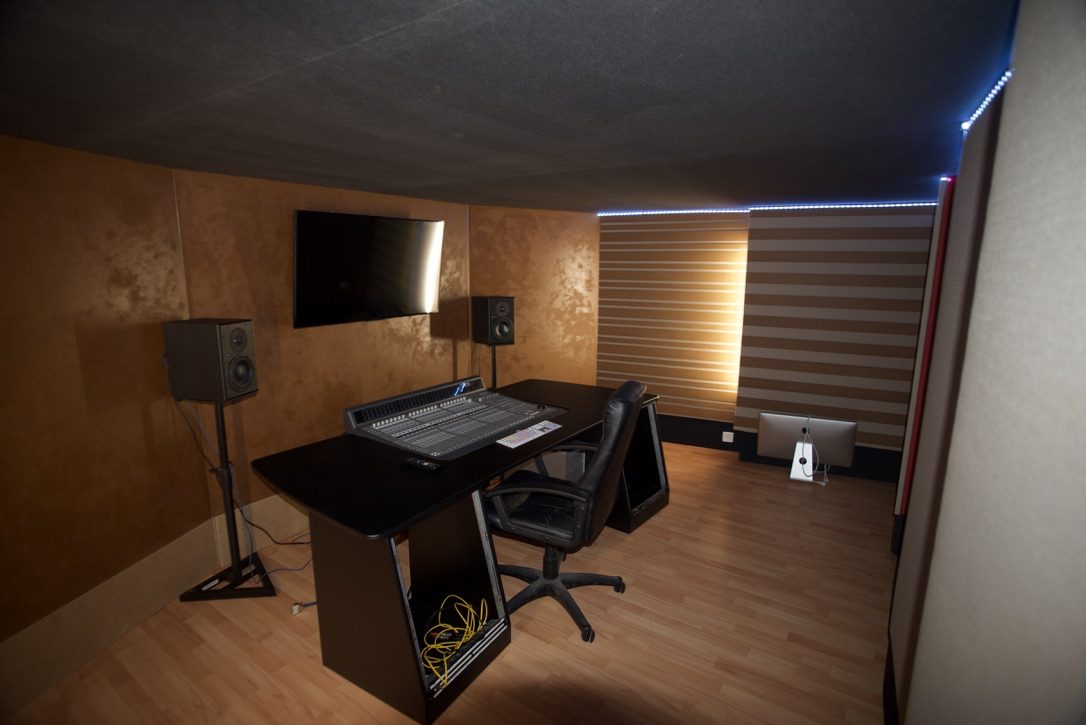 Régie audio dans des tons cuivre avec console, enceintes et éclairage LED