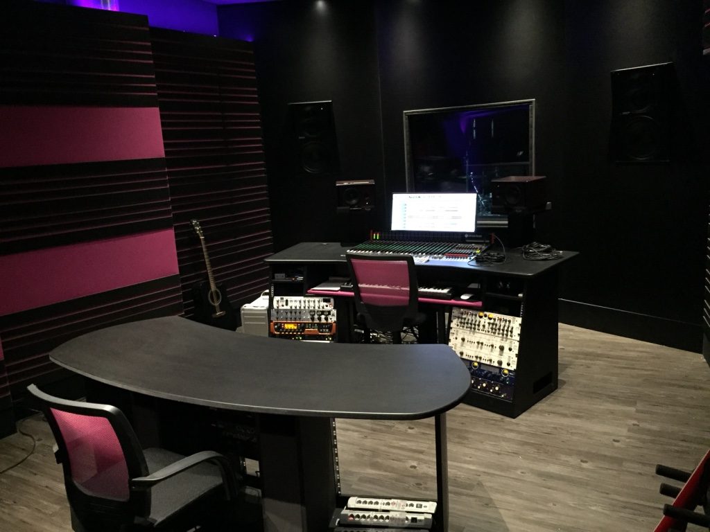Régie rose et noire vue de côté avec poste de travail audio et mobilier technique
